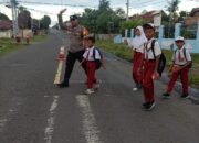 Bhabinkamtibmas Polsek Utan Berikan Pelayanan Prima dengan Membantu Anak-Anak Sekolah Menyeberang Jalan