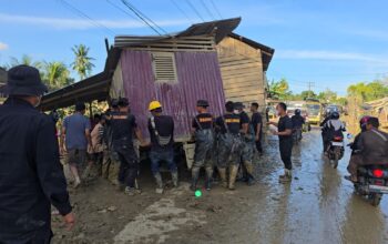 Bahu Membahu, Brimob Pindahkan Rumah Terseret Banjir yang Melintang di Jalan Nasional Tamiang–Langsa